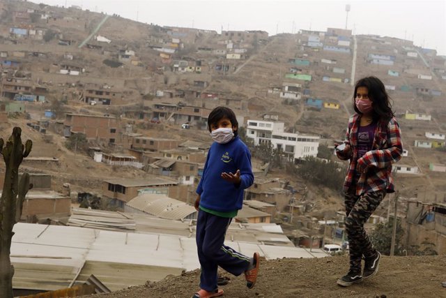 Dos niños con mascarilla caminan por la barriada de Villa Maria del Triunfo, Lima, en medio de la pandemia del coronavirus.