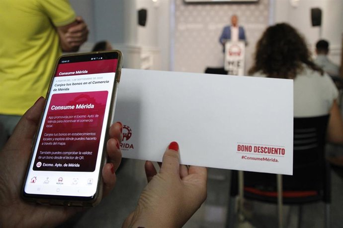 La App y un sobre con uno de los bonos de 20 euros repartidos en las casas de los emeritenses.