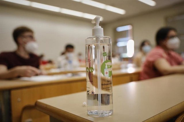 Gel desinfectante en un pupitre mientras estudiantes