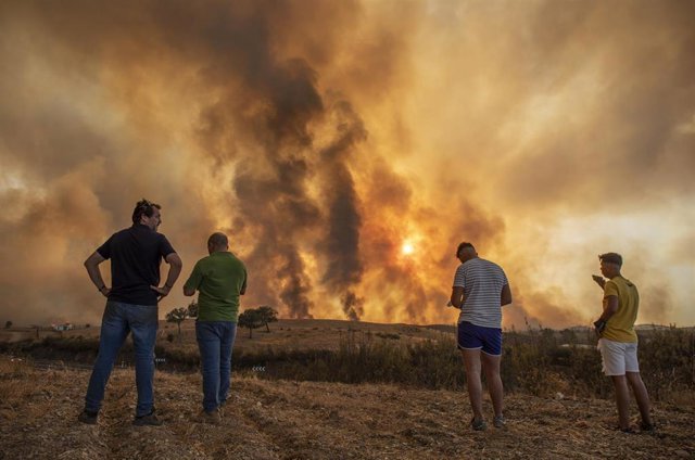 Vecinos observan el incendio forestal declarado en el Paraje Olivargas de Almonaster la Real (Huelva).