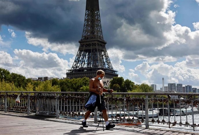Un hombre hace ejericico junto a la Torre Eiffel en París. 