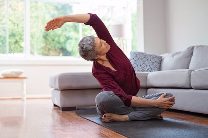 Mujer mayor haciendo yoga en casa.