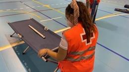 Una voluntaria de Cruz Roja prepara una cama en el albergue instalado para atender a evacuados en el incendio de Las Hurdes