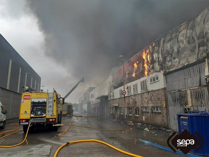 Bomberos trabajan en la extinción del incendio industrial de cinco naves en el polígono de Silvota, Llanera