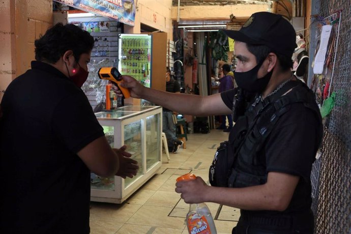 Un hombre se tomar la temperatura a su entrada al Mercado de Hidalgo, en Ciudad de México.