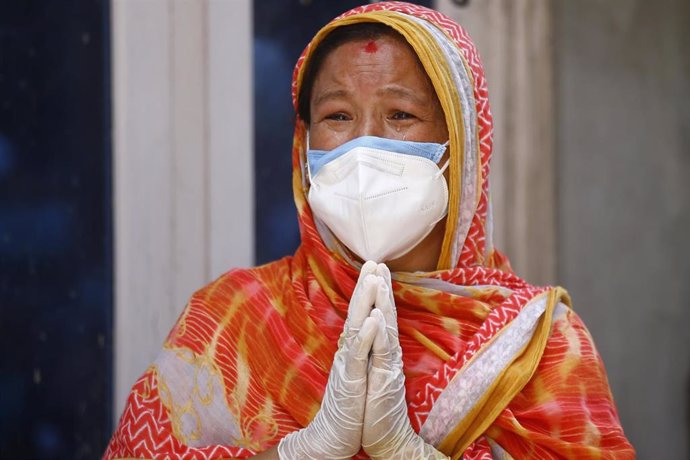 Una mujer con mascarilla llora por la muerte de un familiar por COVID-19 en Nepal