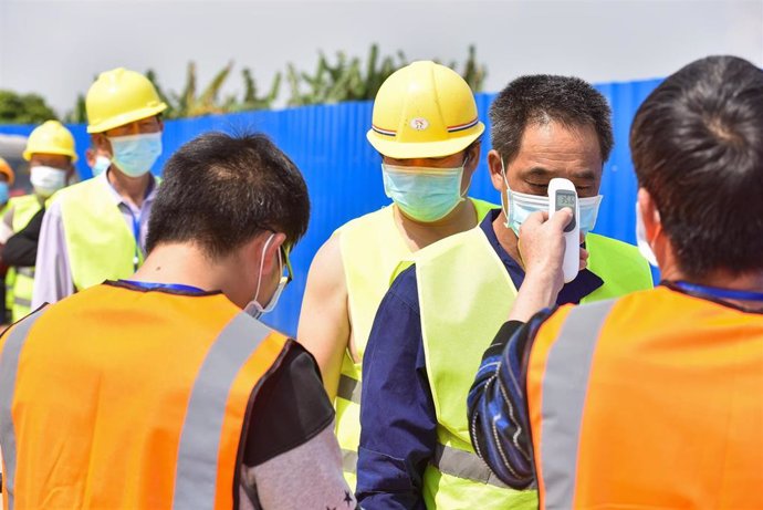 Un grupo de trabajadores de la construcción se somete a pruebas de temperatura antes de iniciar su jornada laboral.