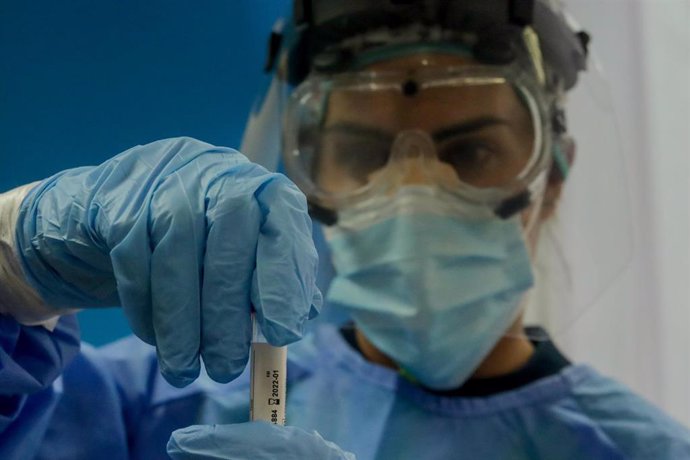 Una trabajadora sanitaria sostiene una probeta con una prueba PCR 