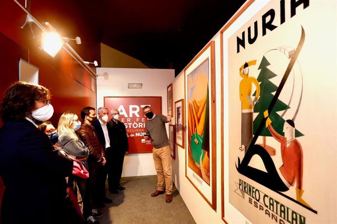 El propietario del cartel inédito y director general de Comunicación del Govern, Jaume Clotet, muestra el cartel al presidente de FGC y otras autoridades.