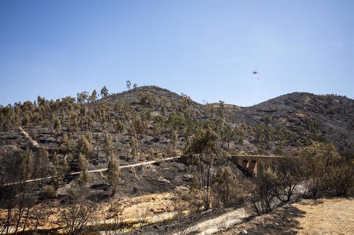 Helicóptero del Infoca realiza vuelos de refresco cerca de la N-435 minutos después de ser abierta al tráfico, tras el incendio forestal de Almonaster la Real (Huelva).