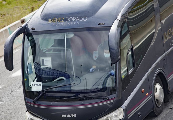 Un conductor de autobús totalmente protegido conduce por una carretera madrileña