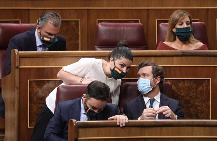 El portavoz de Vox en el Congreso de los Diputados, Iván Espinosa de los Monteros, habla con la secretaria general de Vox en el Congreso, Macarena Olona, junto al presidente de Vox, Santiago Abascal, durante una sesión plenaria en el Congreso