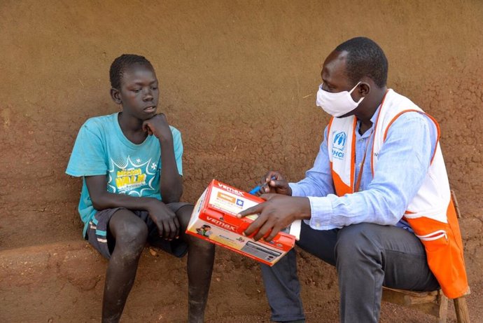 Un trabajador de World Vision entrega una radio a un niño en Uganda