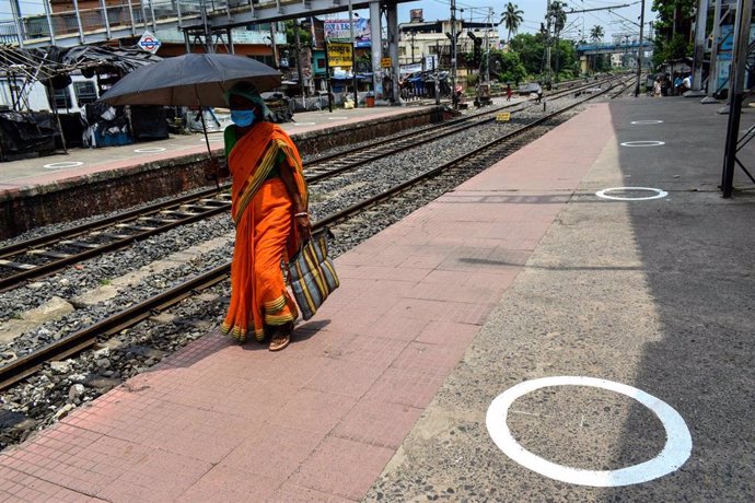Una mujer con mascarilla en una estación de tren en Calcuta
