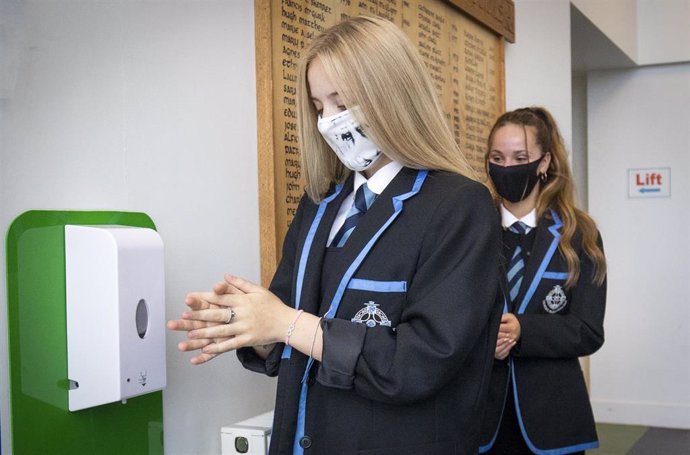 Estudiantes con mascarilla se desinfectan las manos en un instituto de Escocia