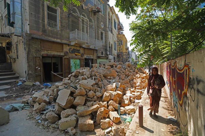 Una mujer camina por una calle de Beirut llena de escombros tras la explosión en el puerto