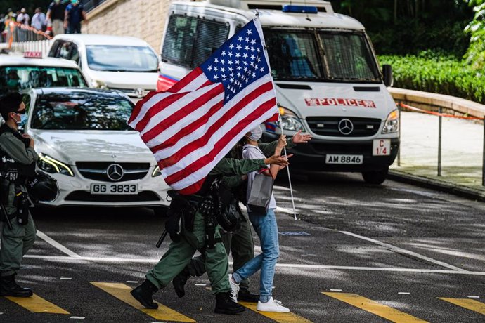 04 July 2020, China, Hong Kong: Policemen lead away a woman waving the US flag outside the Consulate General of the United States in defiance of the newly introduced National Security Law. Photo: Keith Tsuji/ZUMA Wire/dpa
