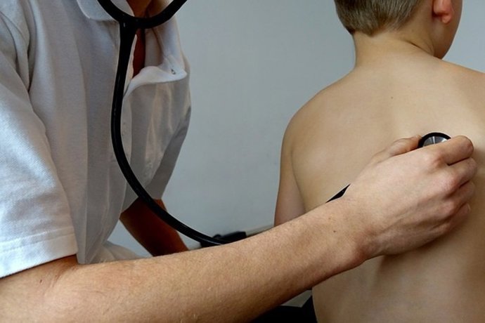 Un médico ausculta a un niño.