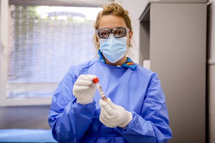 Una trabajadora sanitaria protegida sostiene una de las probetas utilizadas para la realización de PCR 