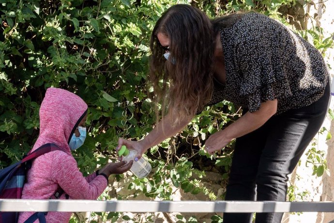 Una profesora y una alumna con mascarillas se desinfectan las manos en Jerusalén. 