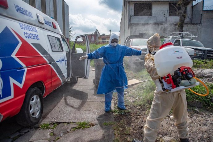 Un trabajador sanitario desinfecta su traje protector por el coronavirus. 