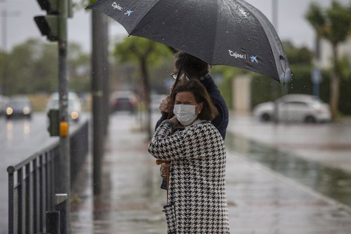 Dos personas sujetan un paraguas durante una tormenta en una imagen tomada durante el Estado de Alarma