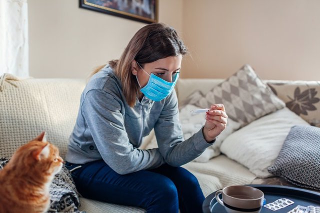 Mujer tomándose la temperatura con un termómetro. Coronavirus, Covid-19.