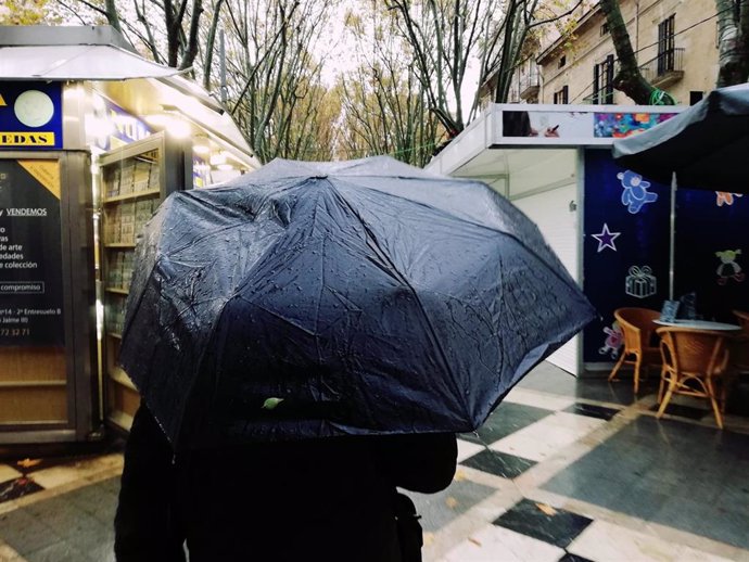 Un hombre pasea por la Rambla de Palma bajo un paraguas un día de lluvia.