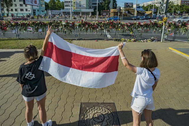 Dos personas con la bandera de Bielorrusia delante del memorial a uno de los fallecidos en las manifestaciones en Minsk