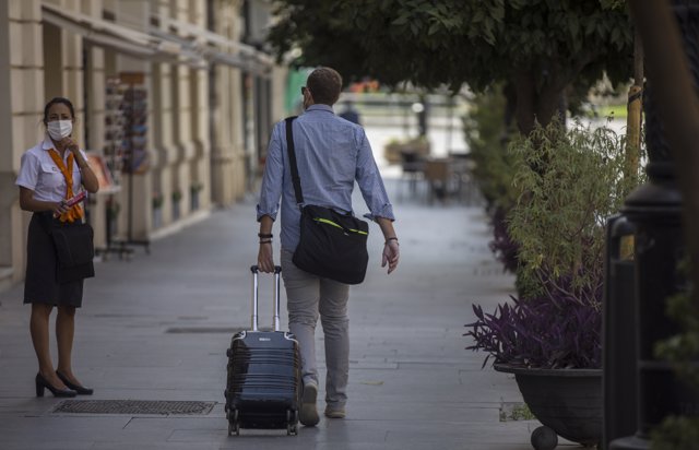 Un hombre con maleta pasea por el centro de la ciudad de Sevilla, (Andalucía, España), a 27 de agosto de 2020.
