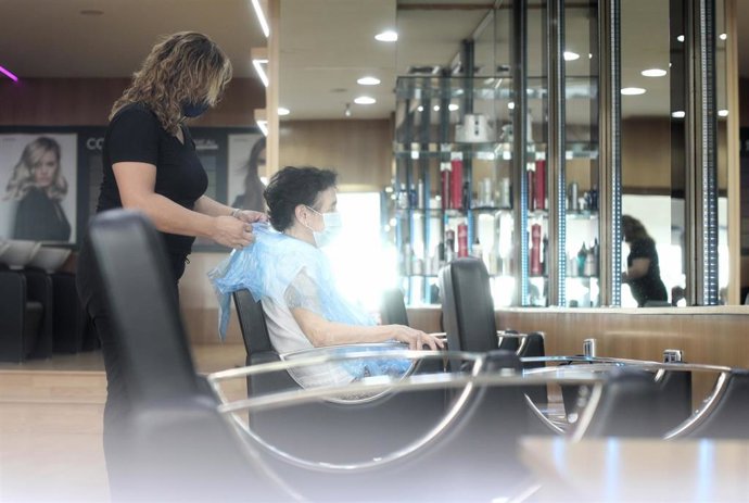 Una peluquera le corta el pelo a una clienta