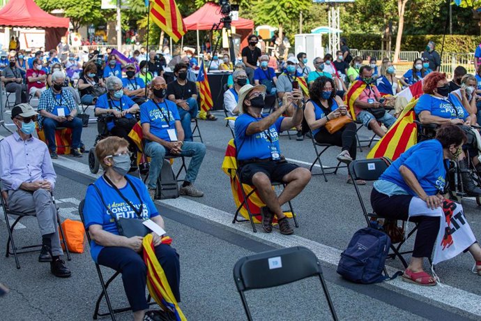 Participantes sentados en las sillas de separación en una concentración de la ANC, mnium y la AMI por la Diada, en la plaza Letamendi de Barcelona