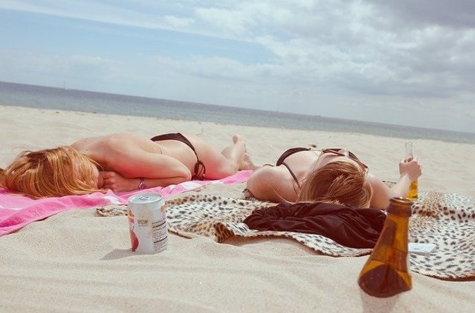 Dos mujeres tomando el sol tumbadas en la playa.