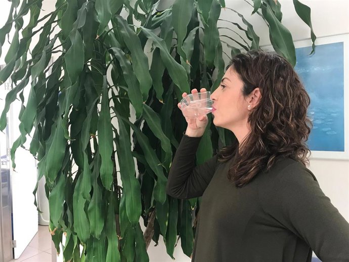 Una mujer bebe un vaso de agua