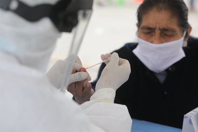 HANDOUT - 11 August 2020, Peru, Villa El Salvador: A medic collects drops of blood from an elderly woman via a testing kit at a coronavirus testing station. Photo: -/Essalud via Agentur Andina/dpa - ACHTUNG: Nur zur redaktionellen Verwendung und nur mit