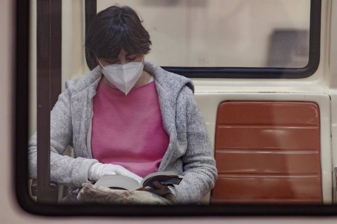 Una pasajera con una mascarilla lee en un vagón del metro un día después de que Metro de Madrid haya registrado un descenso de viajeros del 81 por ciento en hora punta por la crisis del coronavirus, en Madrid (España) a 23 de abril de 2020.