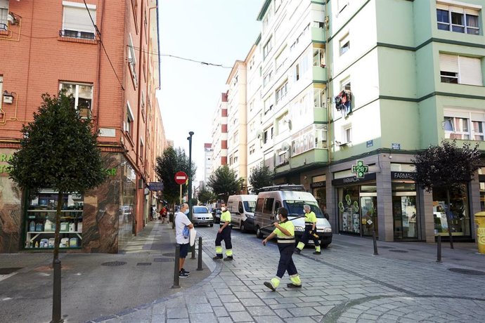 Empleados de la limpieza caminan por las calles del barrio La Inmobiliaria de Torrelavega