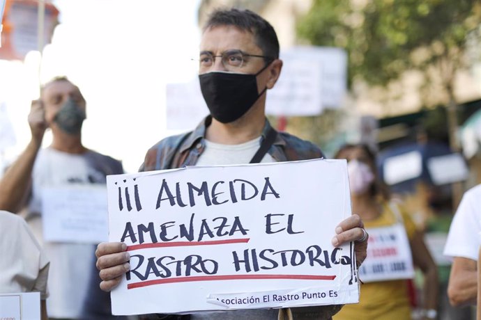 El cofundador de Podemos y director del Instituto 25 de Mayo del partido morado, Juan Carlos Monedero, sostiene una pancarta donde se puede leer "Almeida amenaza el Rastro Histórico" durante el 11 domingo consecutivo de concentraciones organizadas por 