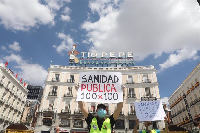 Un miembro del Movimiento Pensionista de Madrid sostiene un cartel en el que se lee 'Sanidad Pública 100 x 100' durante la concentración frente a la Real Casa de Correos en defensa de la sanidad pública, de las residencias públicas y las pensiones "dign