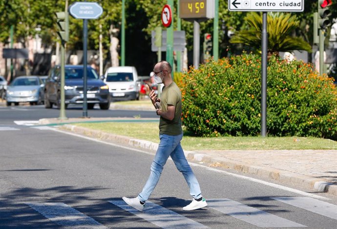 Un peatón paseando con mascarillas cuando el  termómetro marca 44 en la Avenida de la Palmera de Sevilla en un día en el que la ciudad está  en alerta amarilla por altas temperaturas. Sevilla a 22 de junio del 2020