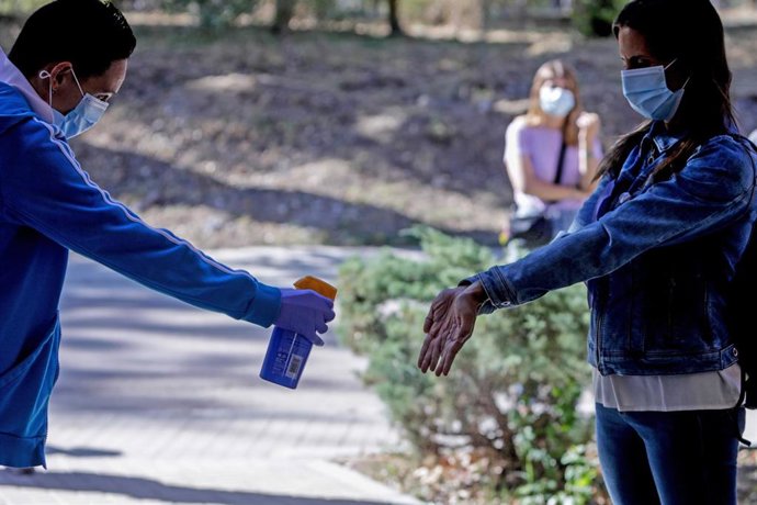 Un sanitario de Cruz Roja administra desinfectante a una mujer antes de  la realización de test rápido de detección de anticuerpos IgG e IgM 