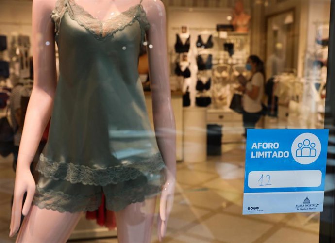 Cartel en la entrada de una tienda de ropa interior en el que se indica que el aforo está limitado a 12 personas, en el Centro Plaza Norte 2, La Cúpula de Madrid, durante el segundo día de la Fase 2 de desescalada, y un día después de reanudar su activi