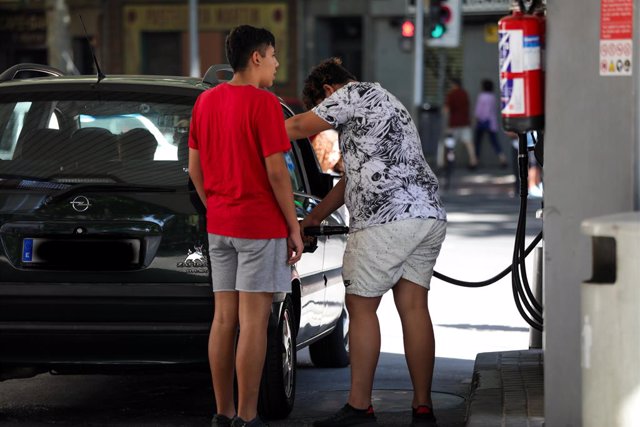 Dos jóvenes ponen gasolina en su coche en una gasolinera de Madrid.