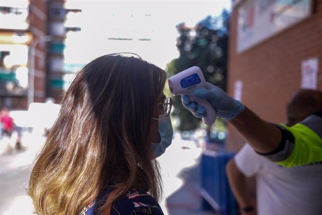 Un trabajador toma la temperatura a una de las personas que acudió a realizarse una prueba PCR al dispositivo instalado en el Centro de Especialidades El Arroyo, en Fuenlabrada.