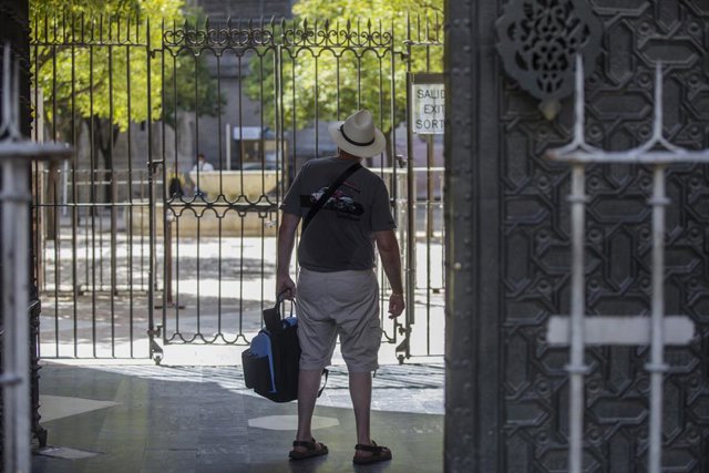 Un turista observa el Patio de los Naranjos desde la salida de la Catedral. En Sevilla (Andalucía, España), a 27 de agosto de 2020.