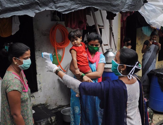 Una trabajadora del sistema de Salud toma la temperatura de un grupo de personas de un asentamiento irregular en el suburbio de Mankhurd, en el este de Bombay, India.