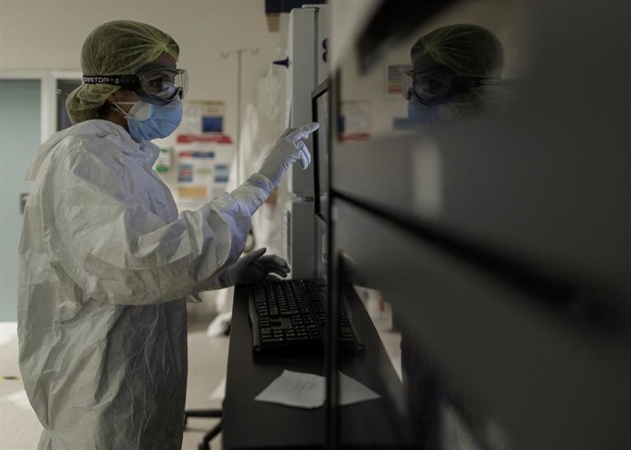 Un trabajador sanitario en la puerta de la habitación de un paciente ingresado en una Unidad de Cuidados Intensivos, foto de archivo