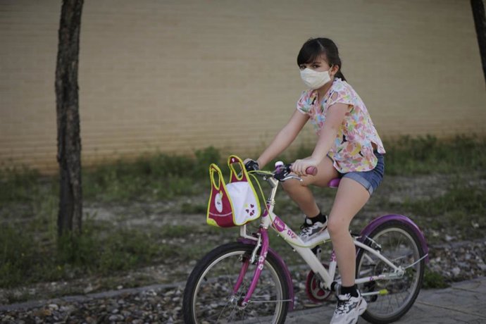 Una niña monta en bicicleta con una mascarilla de protección. En Madrid (España), a 20 de mayo de 2020.