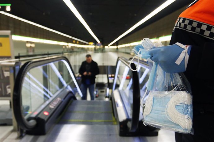 Voluntario de Protección Civil reparte mascarillas entre trabajadores usuarios del metro de Málaga