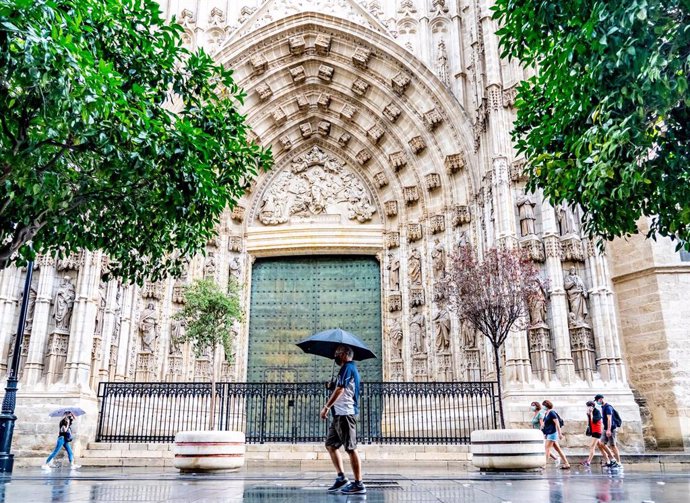 Ciudadanos con paraguas  por  la  Av. de la Constitución, en una mañana lluviosa en  Sevilla a 18 de septiembre 2020